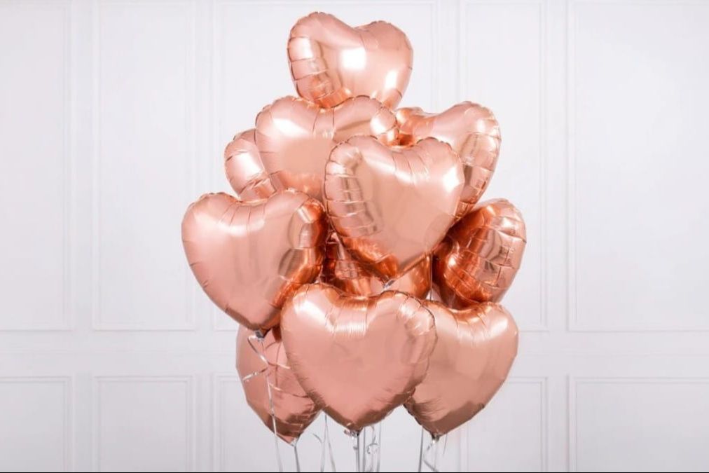 A set of rose gold foil balloons in the shape of hearts